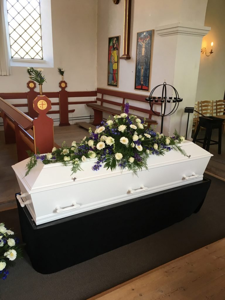 Hvid kiste med blomster i kirke