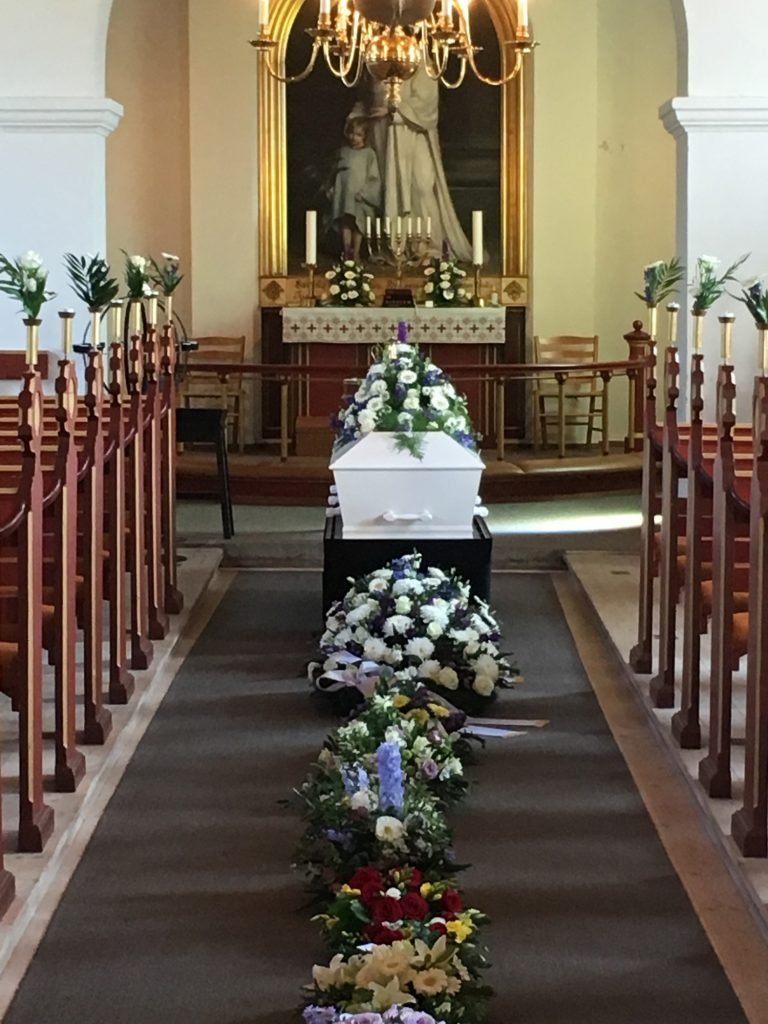 Hvid kiste med blomster i kirke