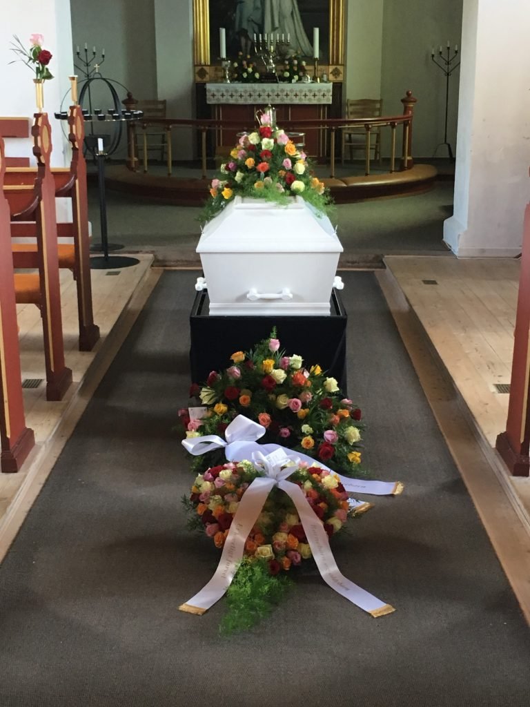 Hvid kiste med blomster i kirke