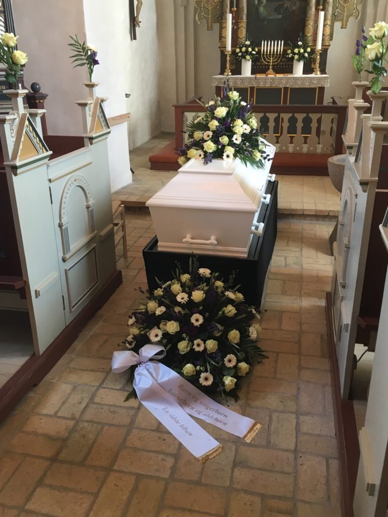Hvid kiste med blomster i kirke